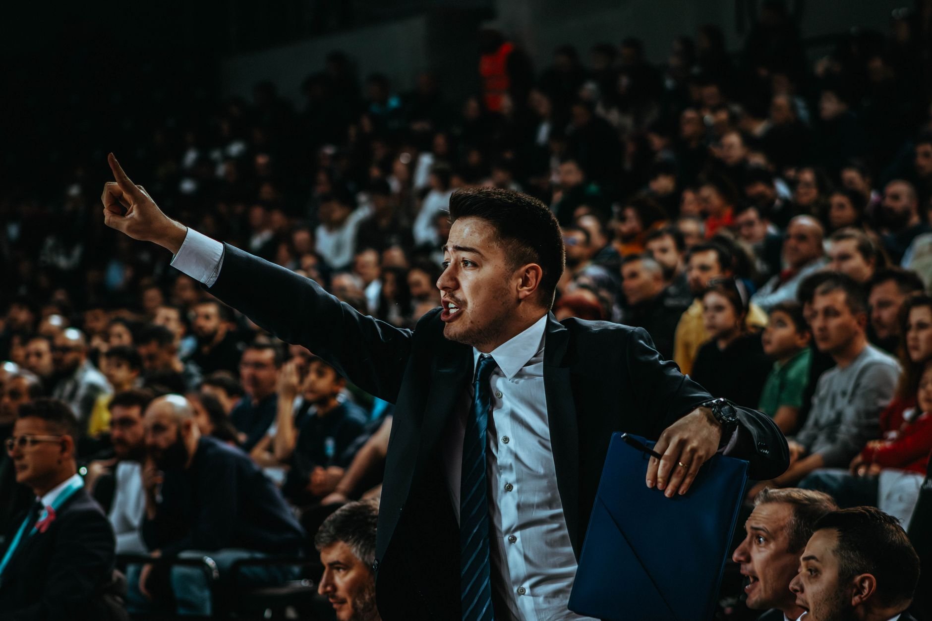 Basketball game in a crowded arena with coach directing play