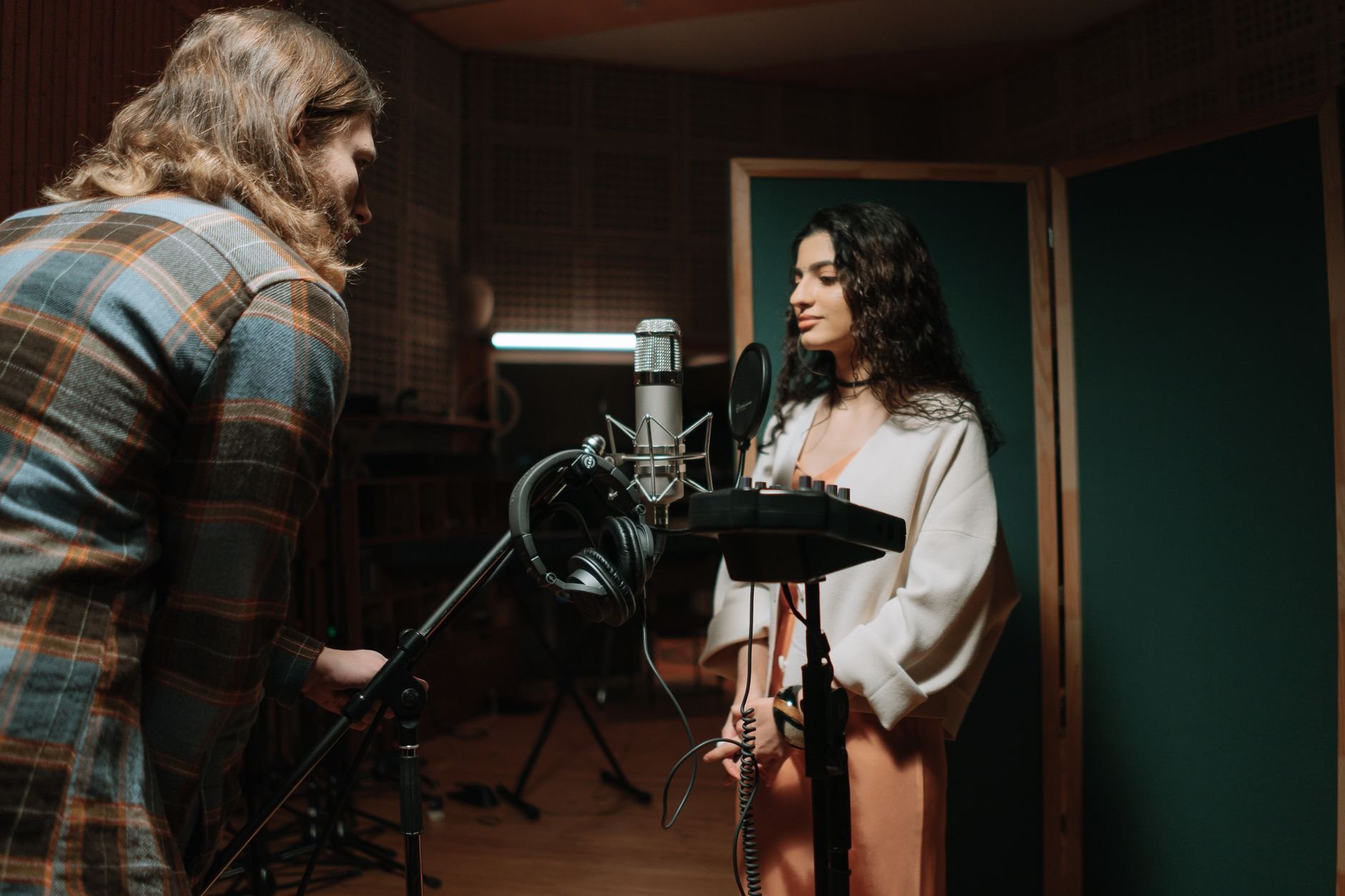 A woman recording vocals in a professional music studio setting